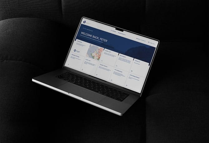 Laptop on dark fabric showing a business dashboard with user welcome message and various data widgets on screen.